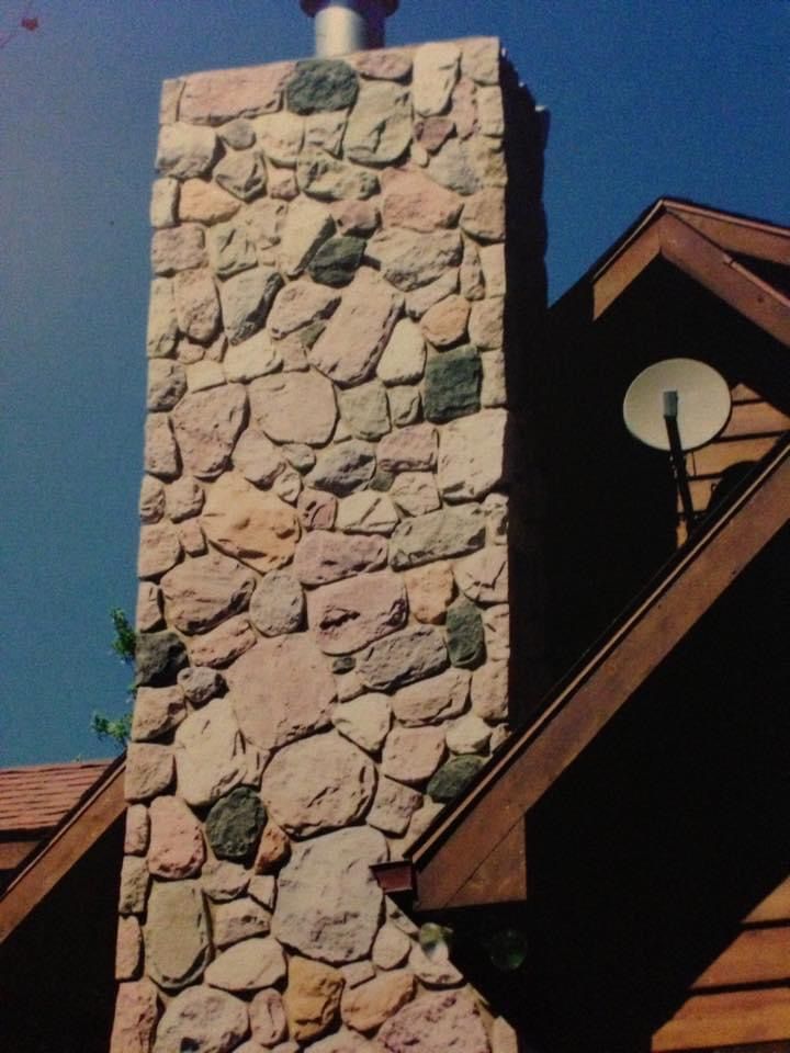 A large stone chimney on the side of a house