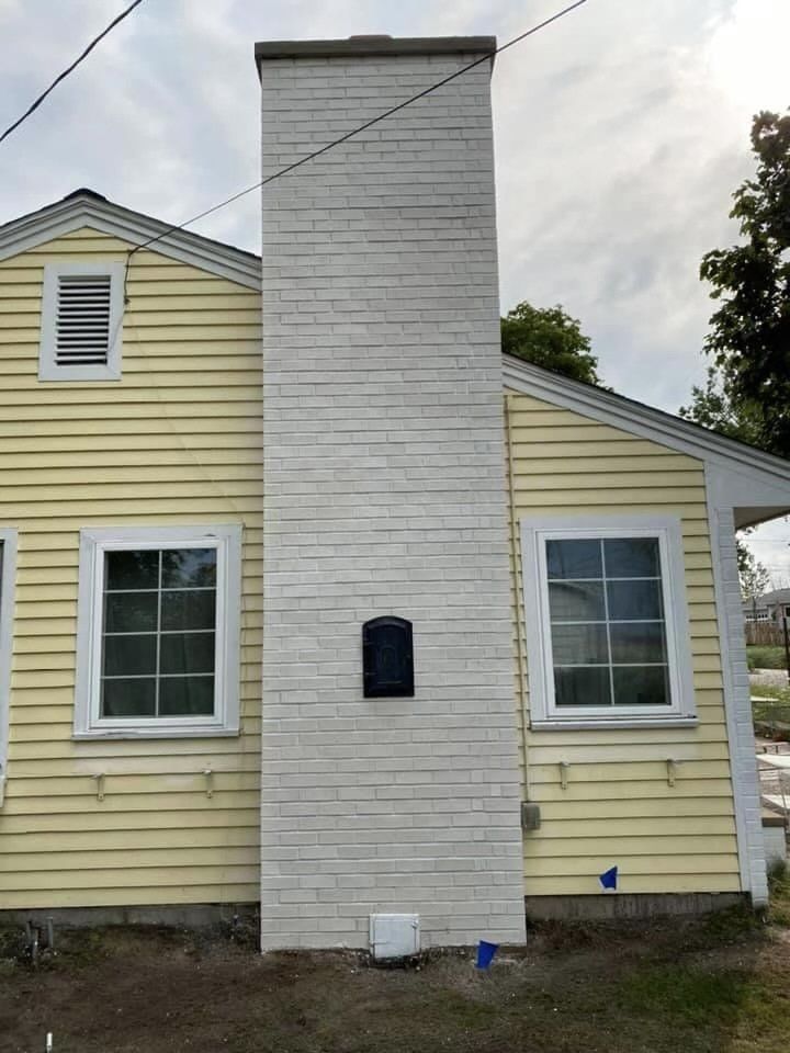 A yellow house with a white chimney on the side of it.
