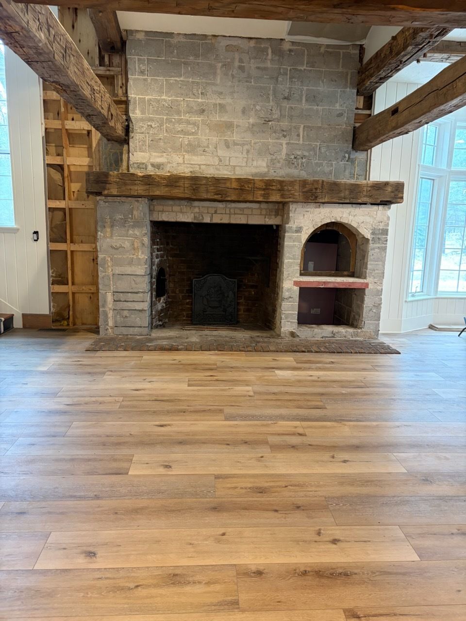 Rustic stone fireplace with wooden mantel in a bright room with wide plank wood floors