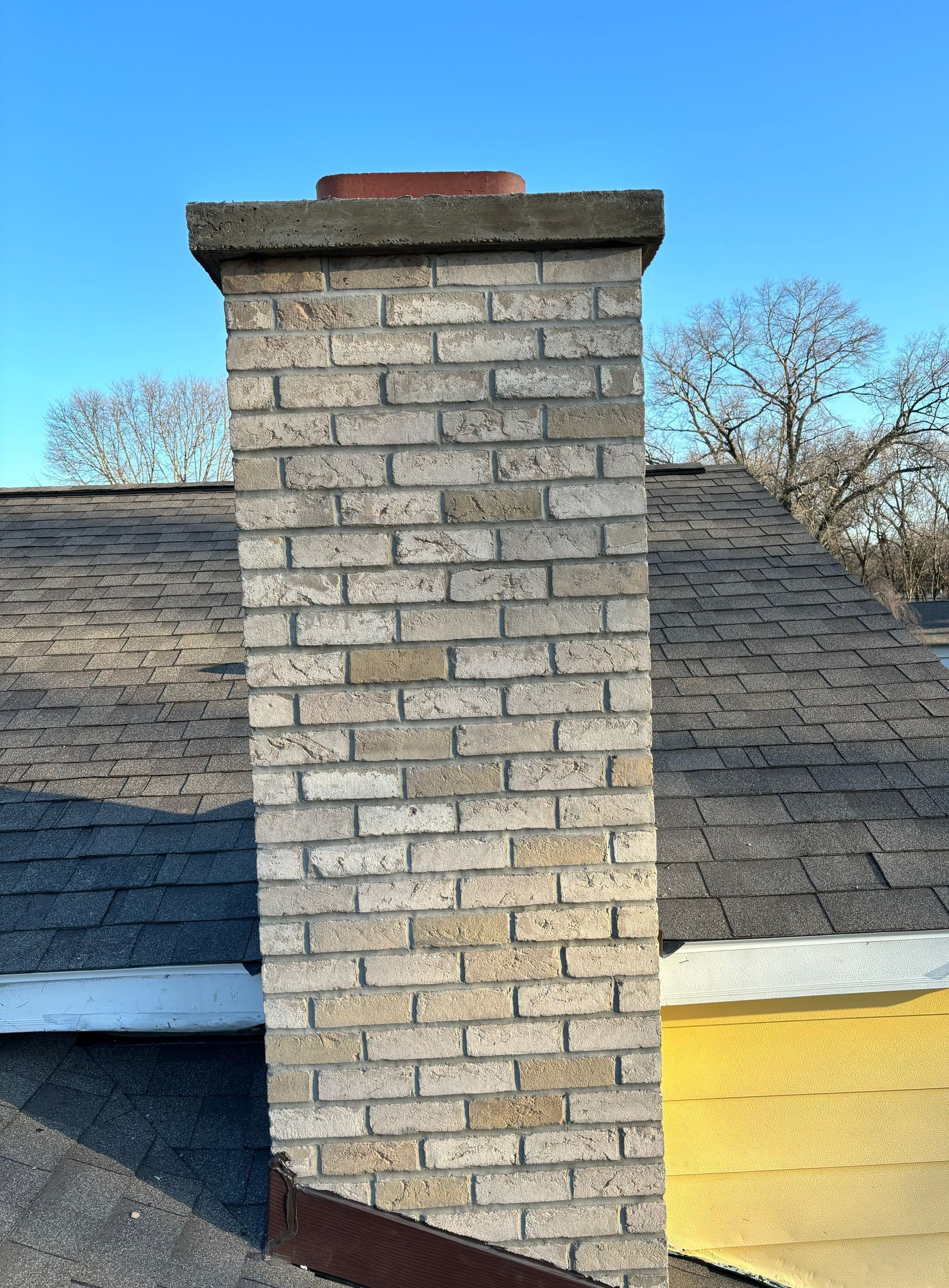 A brick chimney is sitting on top of a roof.