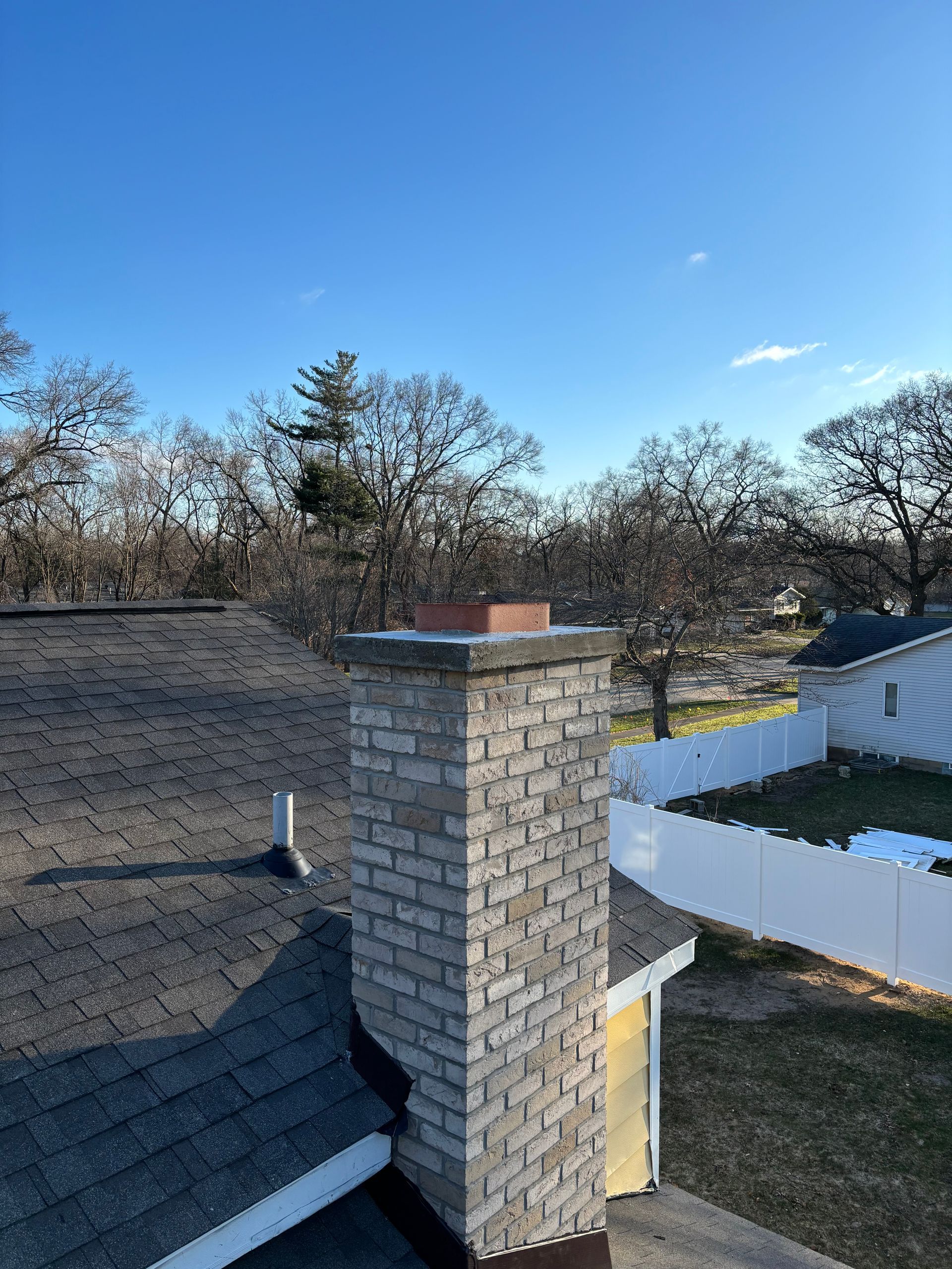 A chimney on the roof of a house with a blue sky in the background.