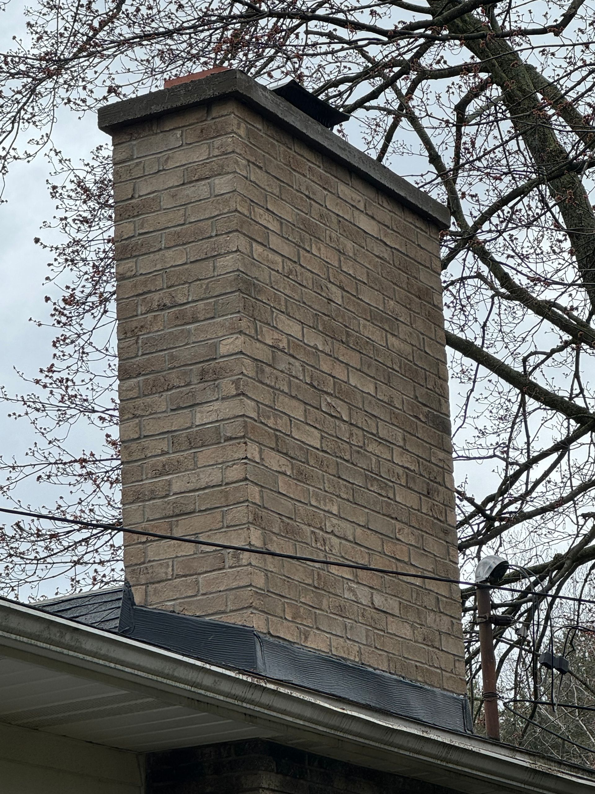 A large brick chimney is on the roof of a house.