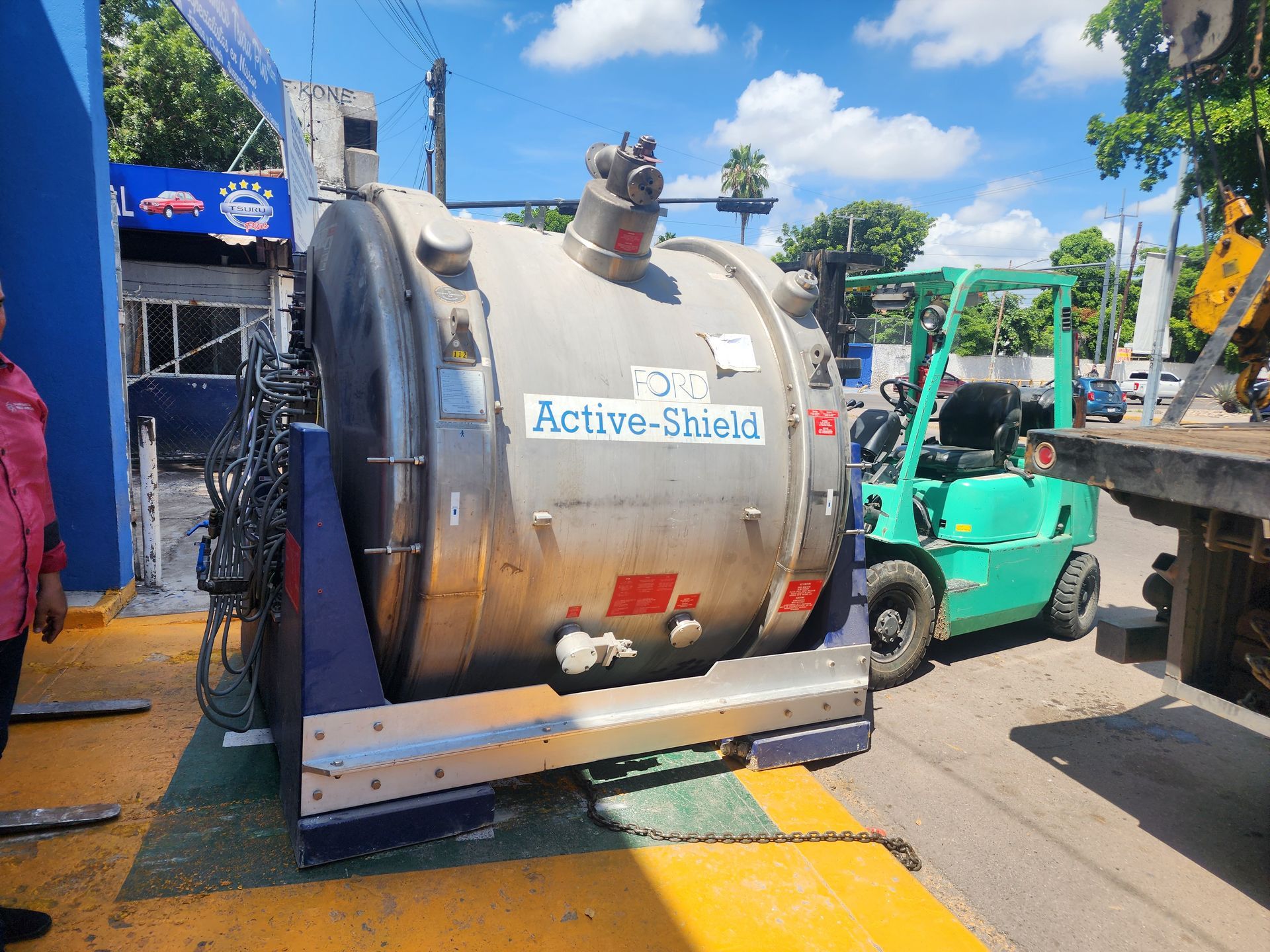 Una carretilla elevadora verde transporta un objeto metálico grande que dice 