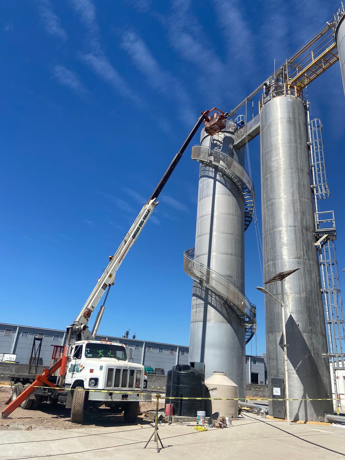 Un camión con una grúa acoplada está estacionado delante de un gran edificio.
