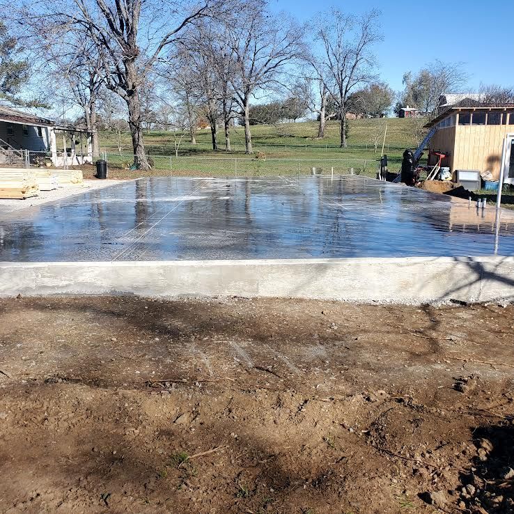 Freshly poured concrete foundation; wet surface reflecting sky. Outdoors, sunny day.