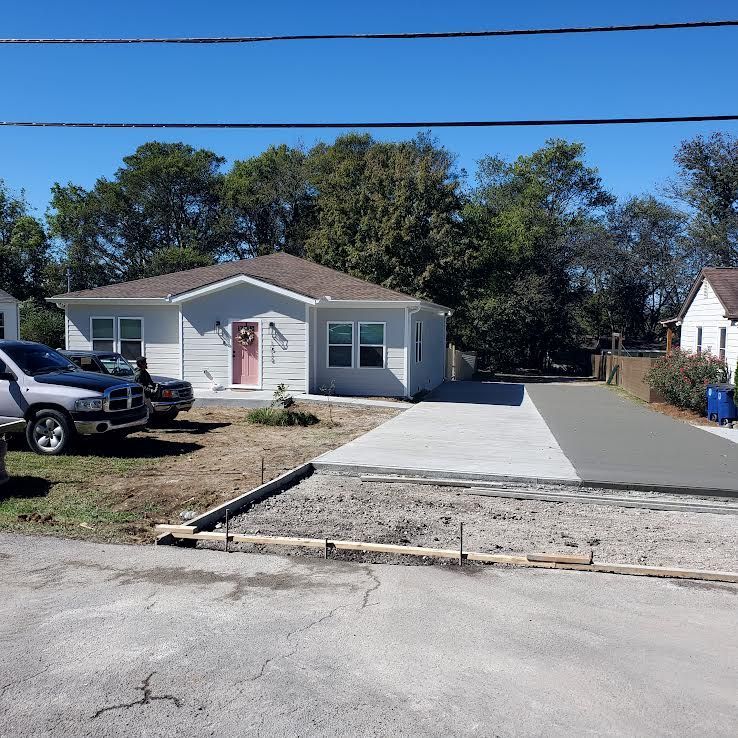 Gray house with new concrete driveway and a gray pickup truck parked nearby.