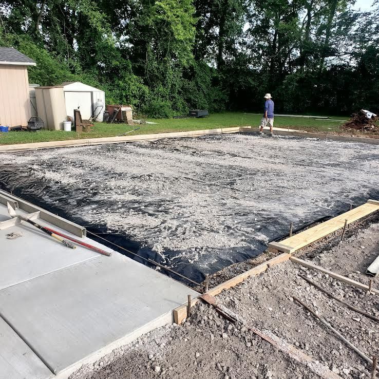 Construction site with a concrete slab, forms, and a person in the background.