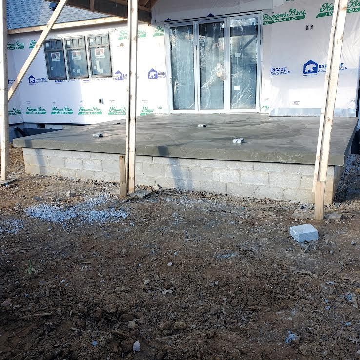 Concrete patio under construction, with cinder block base, dirt ground.