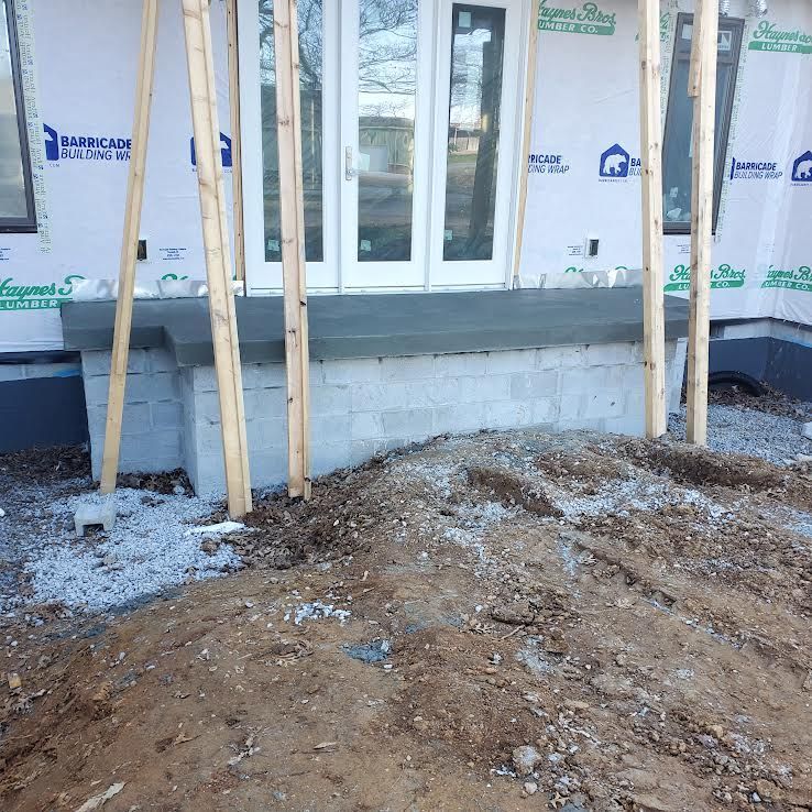 Construction site with unfinished concrete steps and wooden supports near a white door.