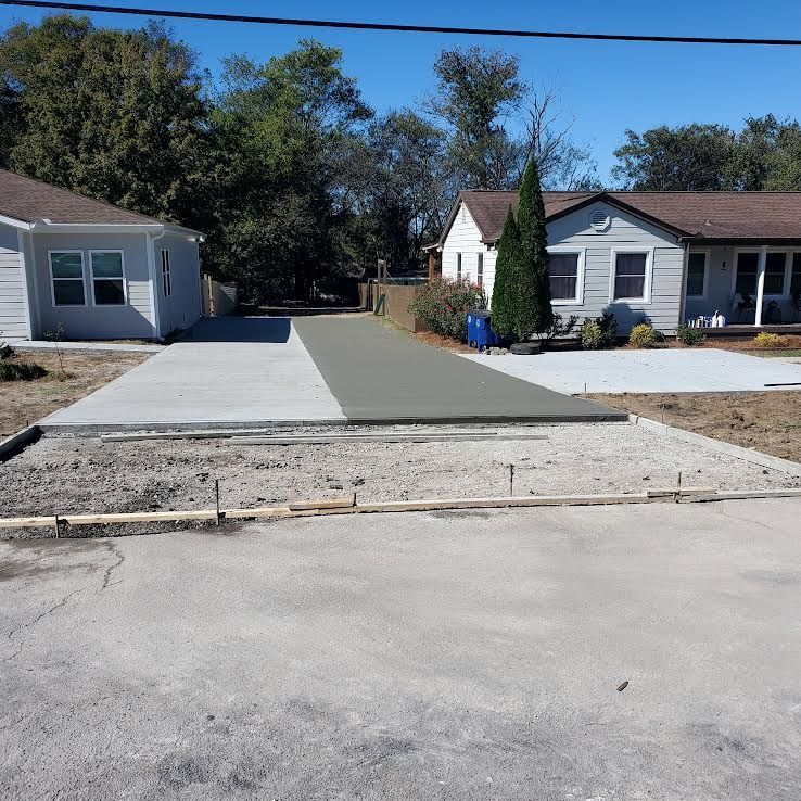 Freshly poured concrete driveway in front of houses; partly gray and partly wet.