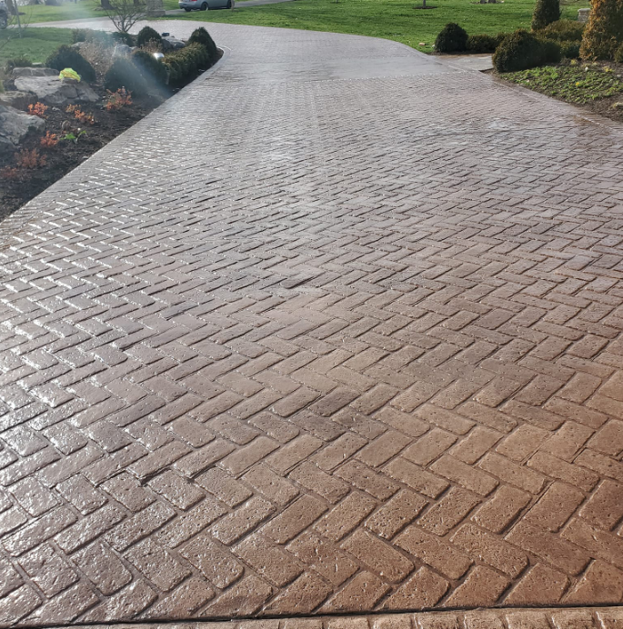 Herringbone brick driveway. Brown bricks in a diagonal pattern, leading to green lawn.