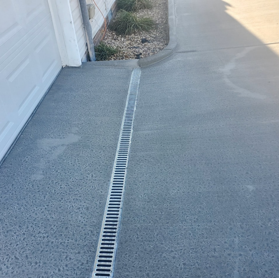 Concrete driveway with a long, linear drain along the driveway's center.