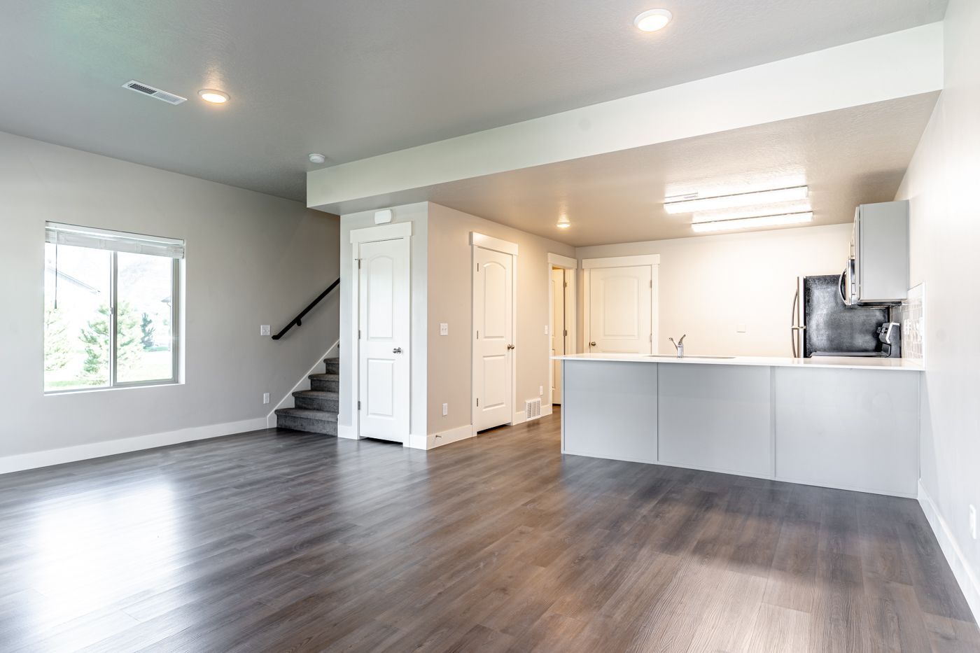 Open living area with kitchen island, stairs, and a large window.