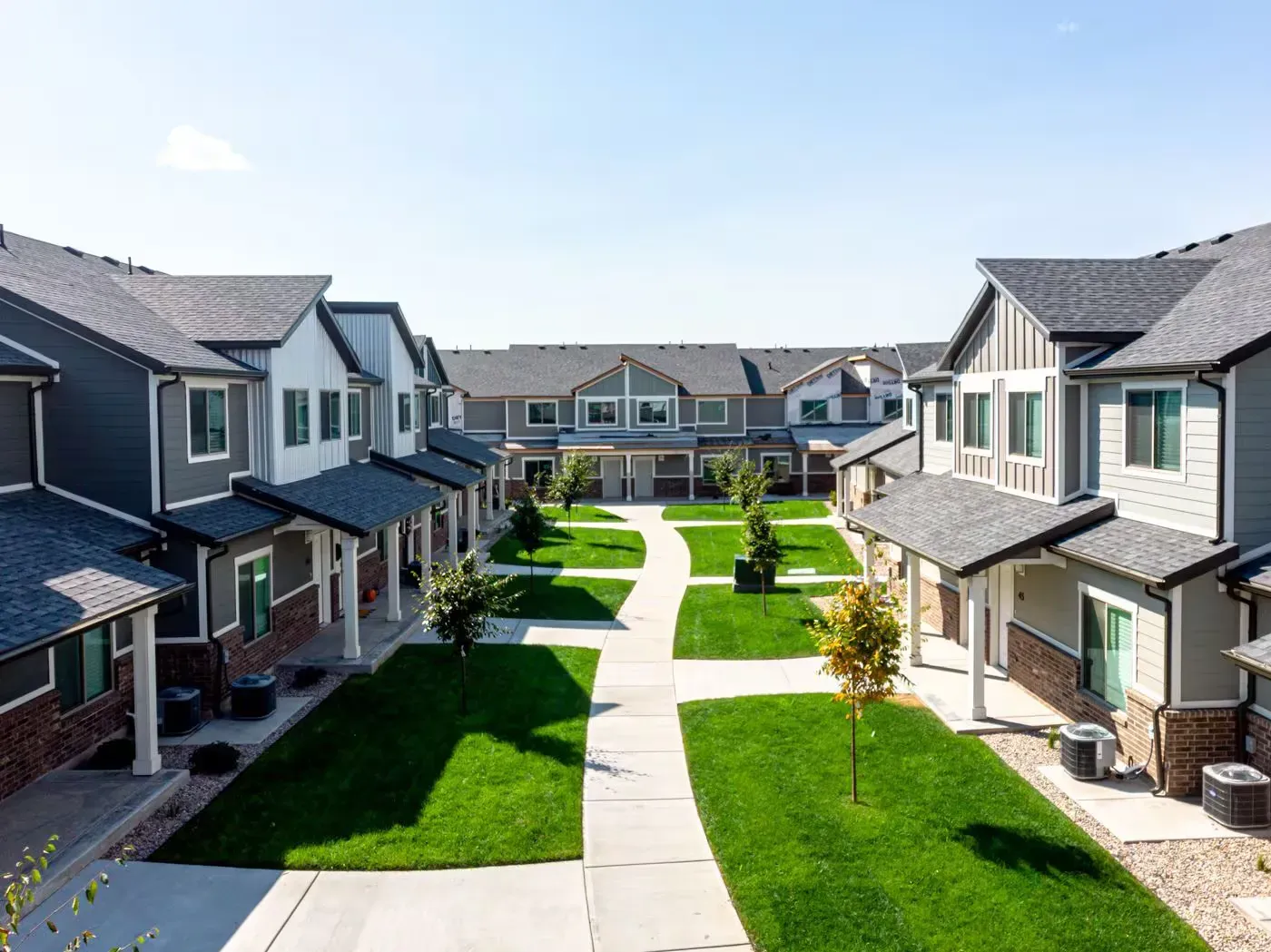 Aerial view of a modern apartment complex courtyard with green lawns and walkways.