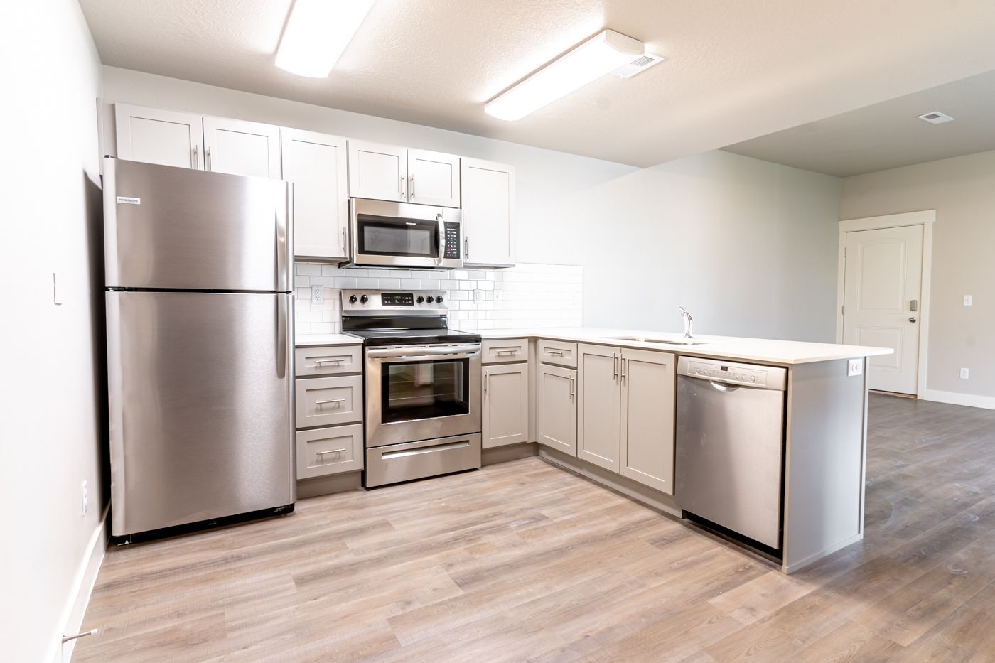Open-concept kitchen with stainless steel appliances and light gray cabinets.