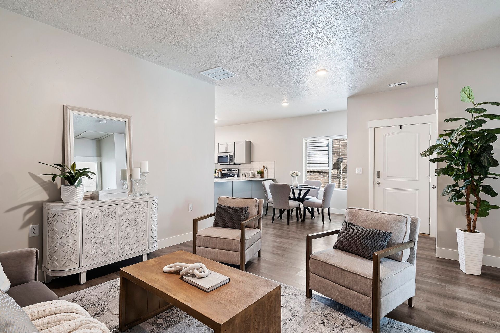 Open-concept living room with beige seating and an open kitchen in a modern apartment.