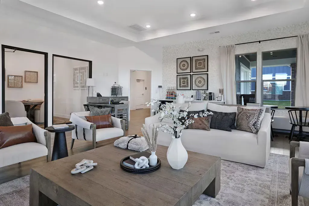 Bright modern resident lounge with white sofas, a large wooden coffee table, and large windows.