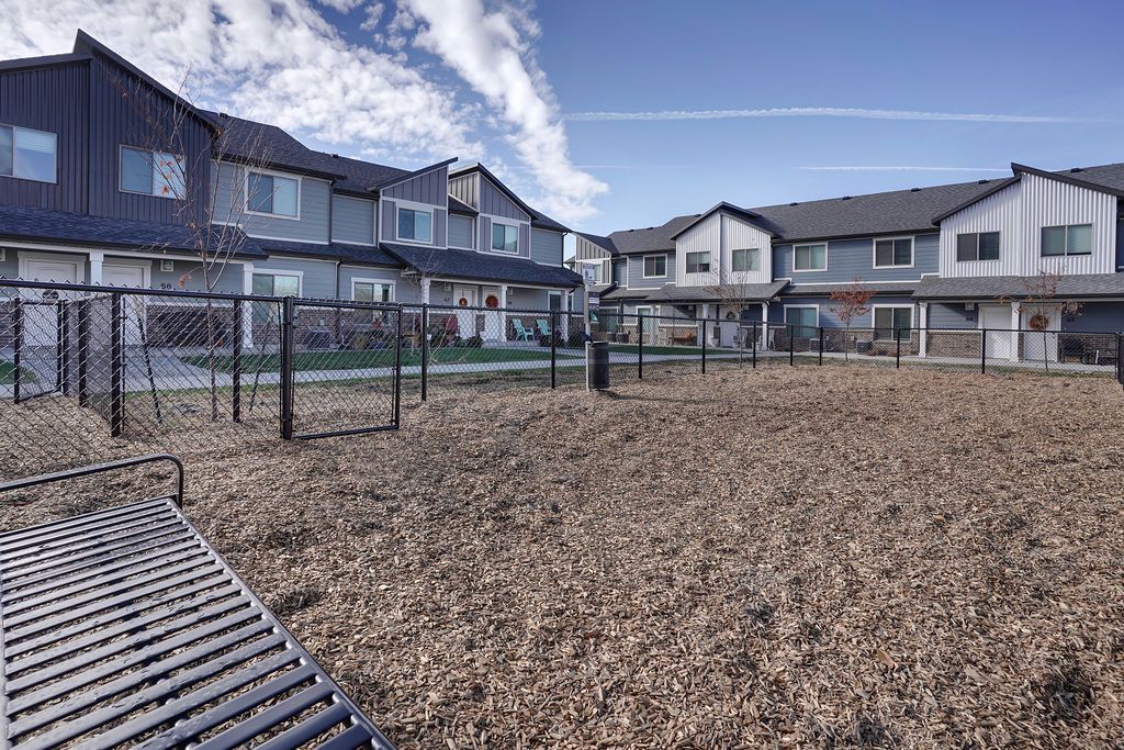 Fenced communal yard with townhome-style apartment buildings in the background.
