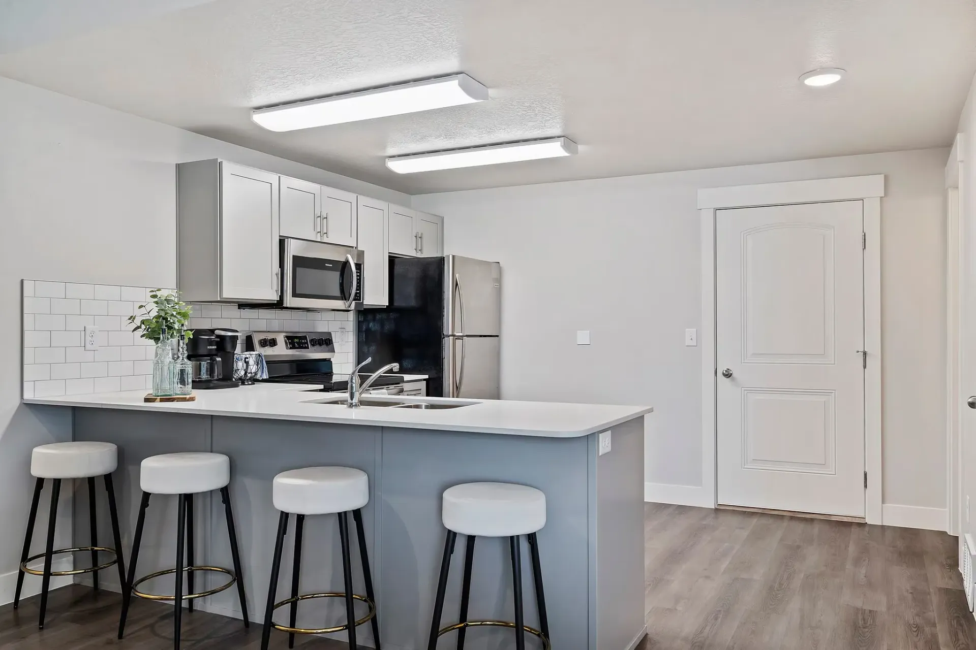 Modern kitchen with white cabinets, stainless steel appliances, and a breakfast bar.