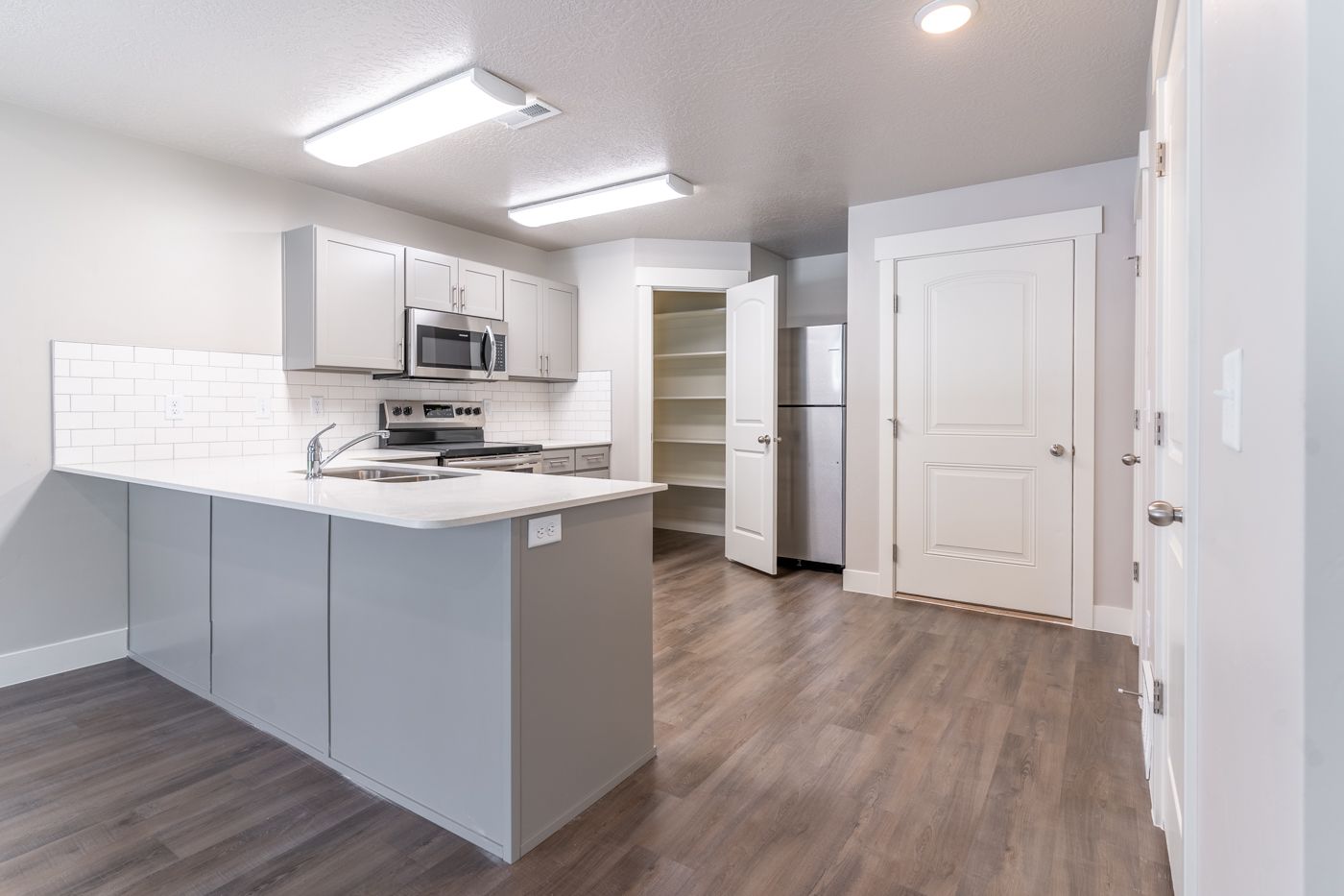 Modern apartment kitchen with an island, white cabinets, and stainless steel appliances.
