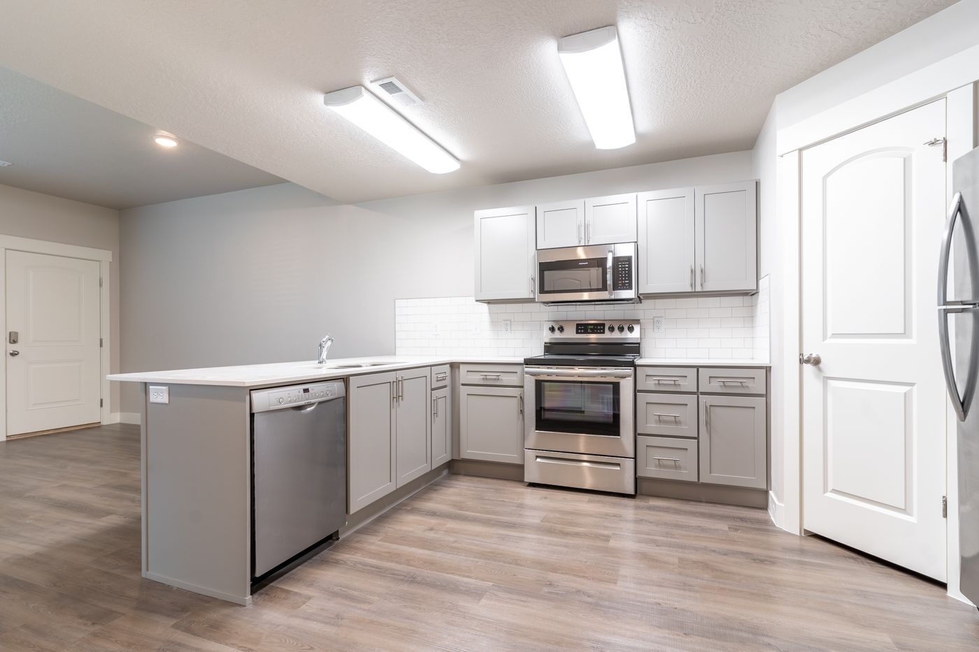Open-concept kitchen with gray cabinets, stainless steel appliances, and an island.