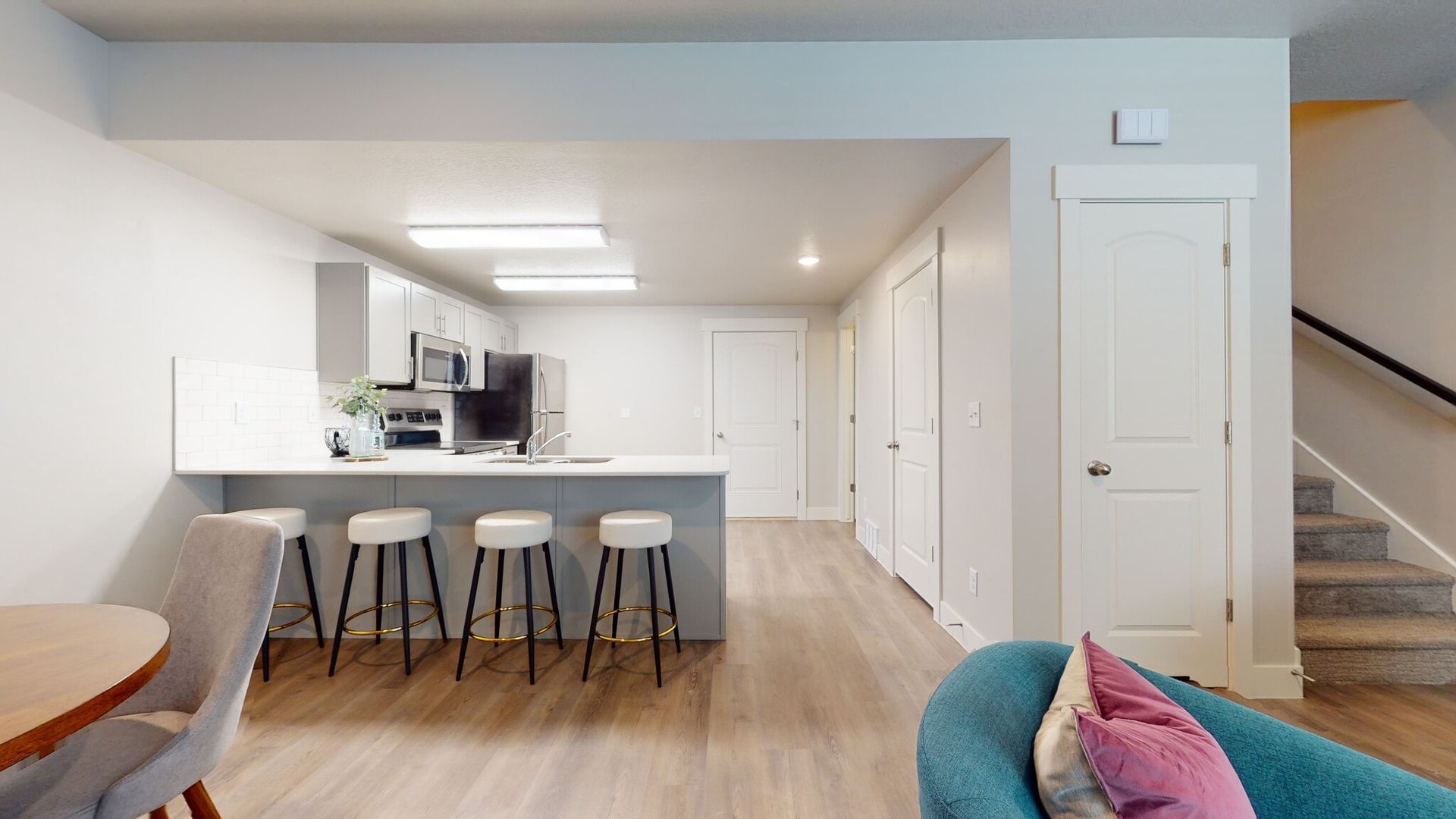 Open-concept kitchen with an island and bar stools in a modern apartment.