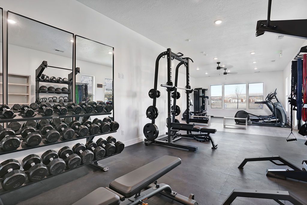 Fitness center in a multifamily community with free weights, benches, and cardio machines.