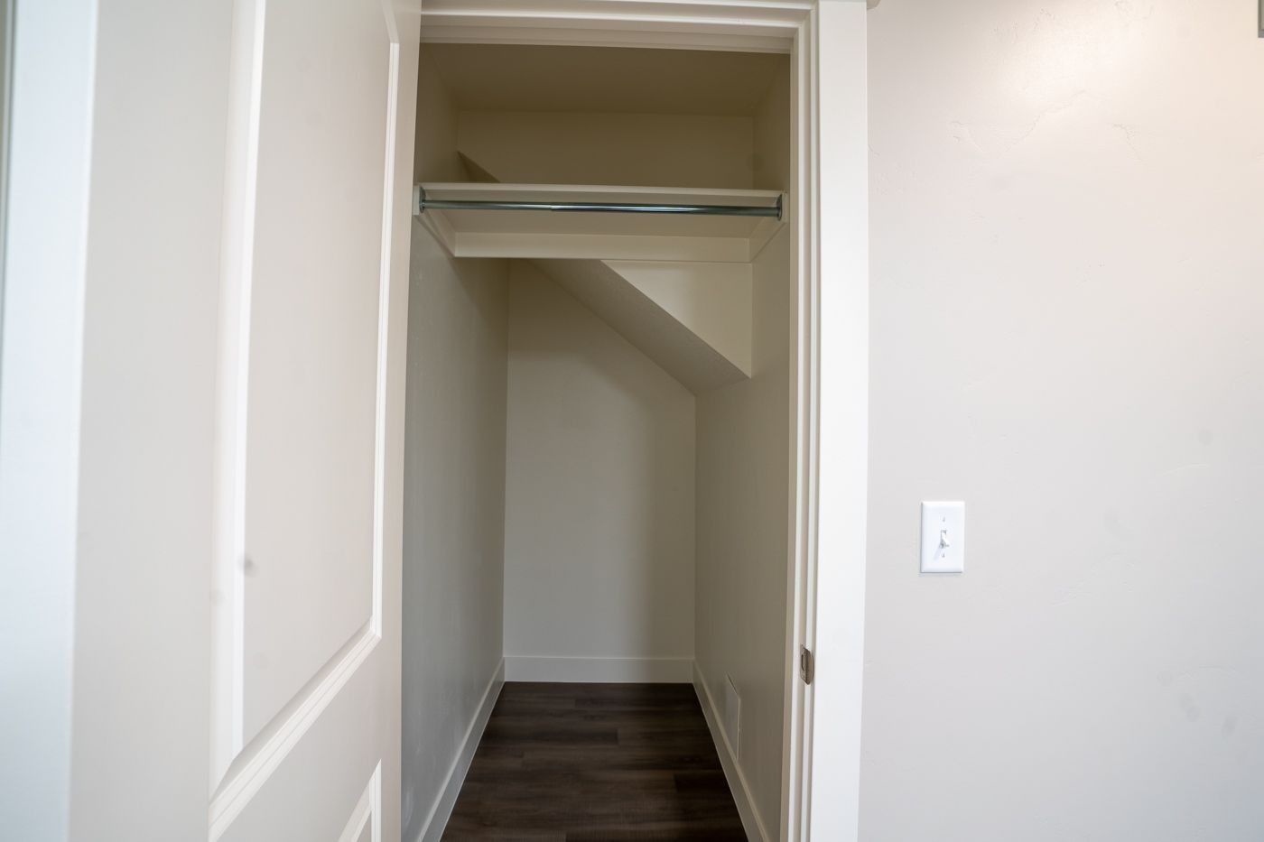 Open reach-in closet with a metal hanging rod and top shelf in an apartment.