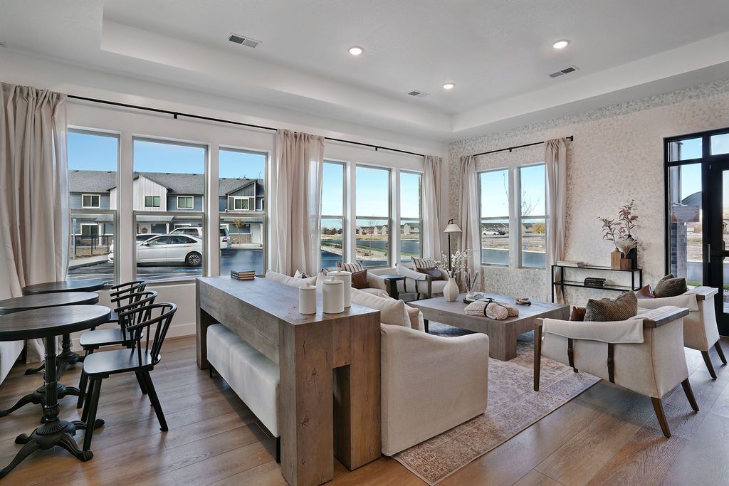 Bright apartment resident lounge with large windows, neutral sofas, and a central coffee table.