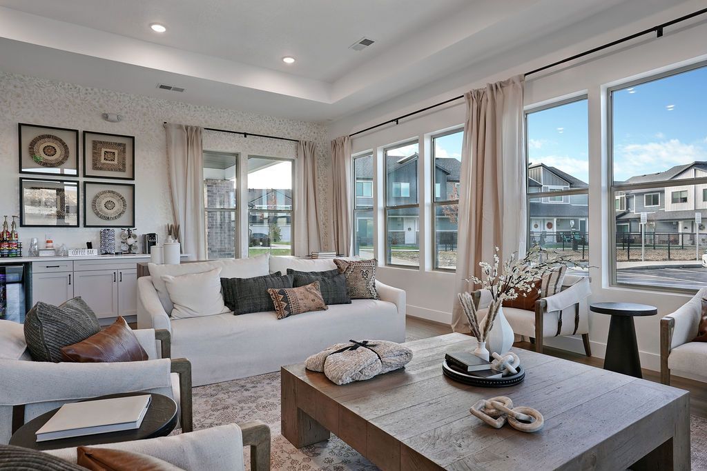 Bright modern apartment lounge room with large windows, white sofa, and wooden coffee table.