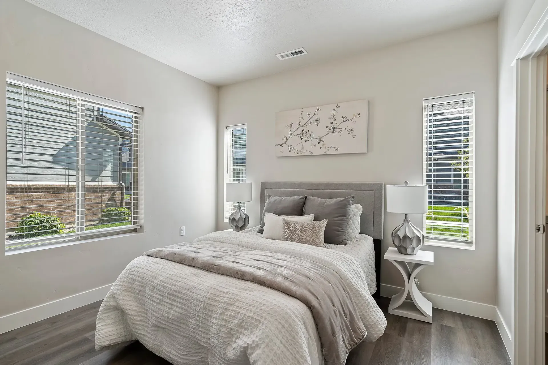 Bedroom in a modern apartment with a bed, two nightstands, and large windows.