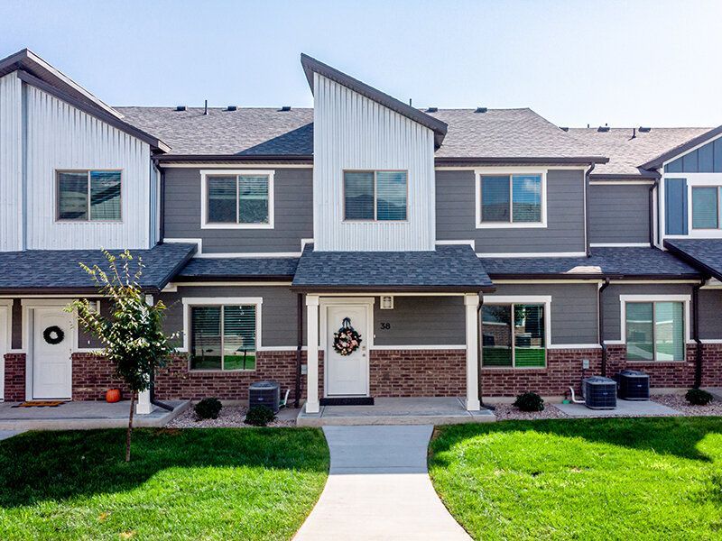 Row of modern townhomes with gray siding, white trim, and brick accents.