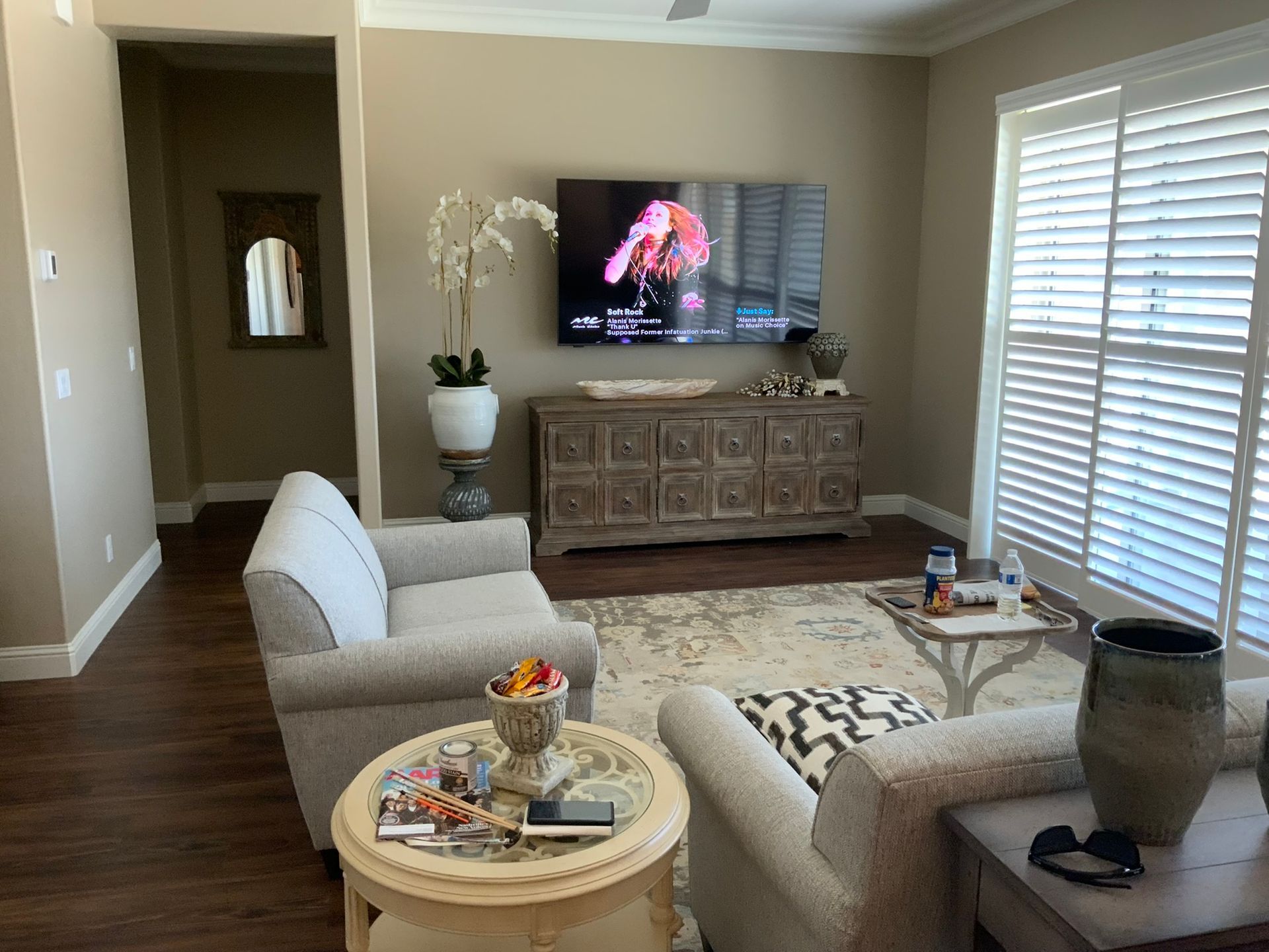 Living room with beige walls, TV above a wooden cabinet, two cream sofas, and a rug.