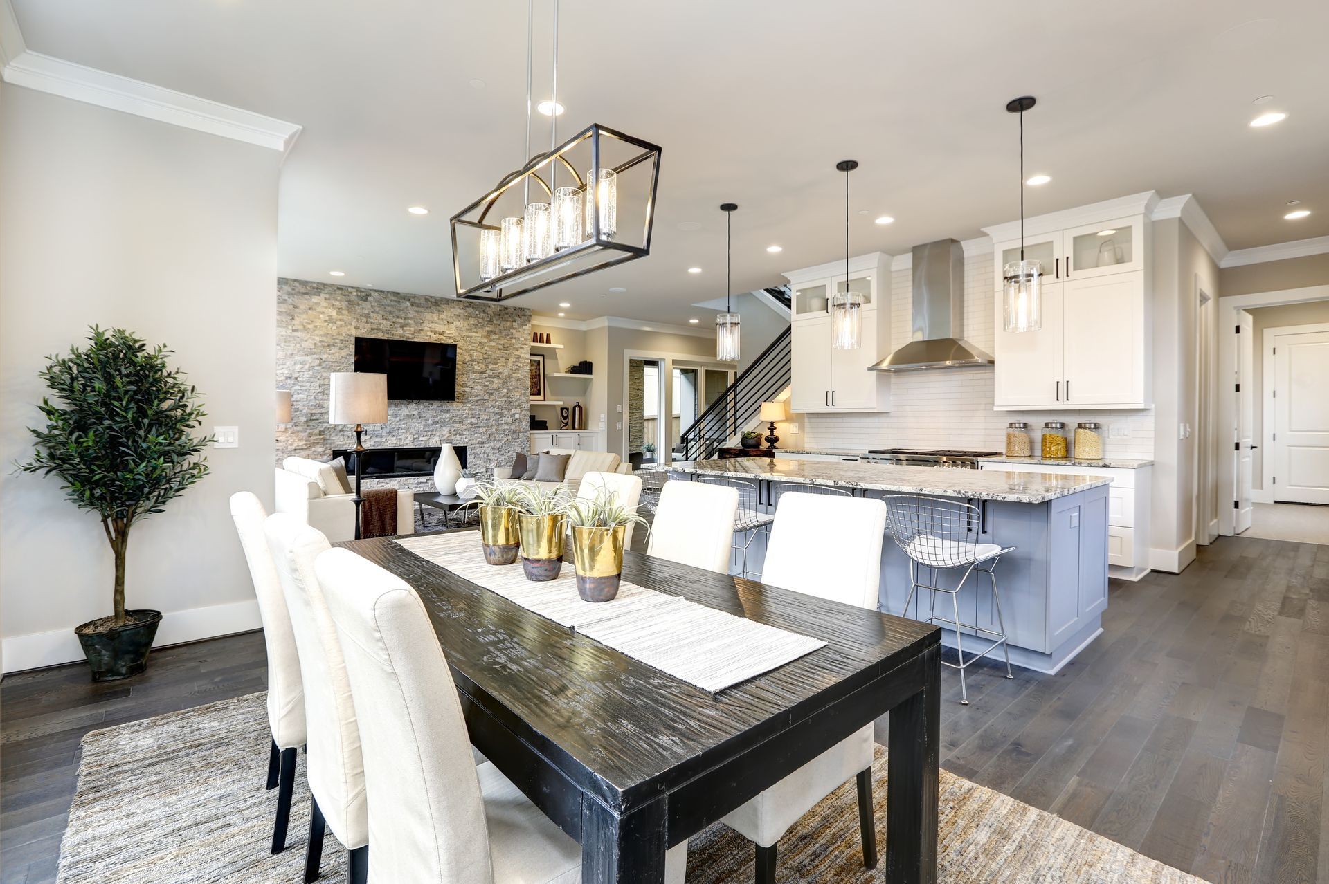 Open-concept kitchen and dining area with dark wood table, white chairs, and modern lighting.