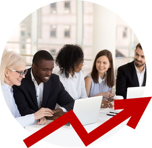 A group of people are sitting around a table with laptops.