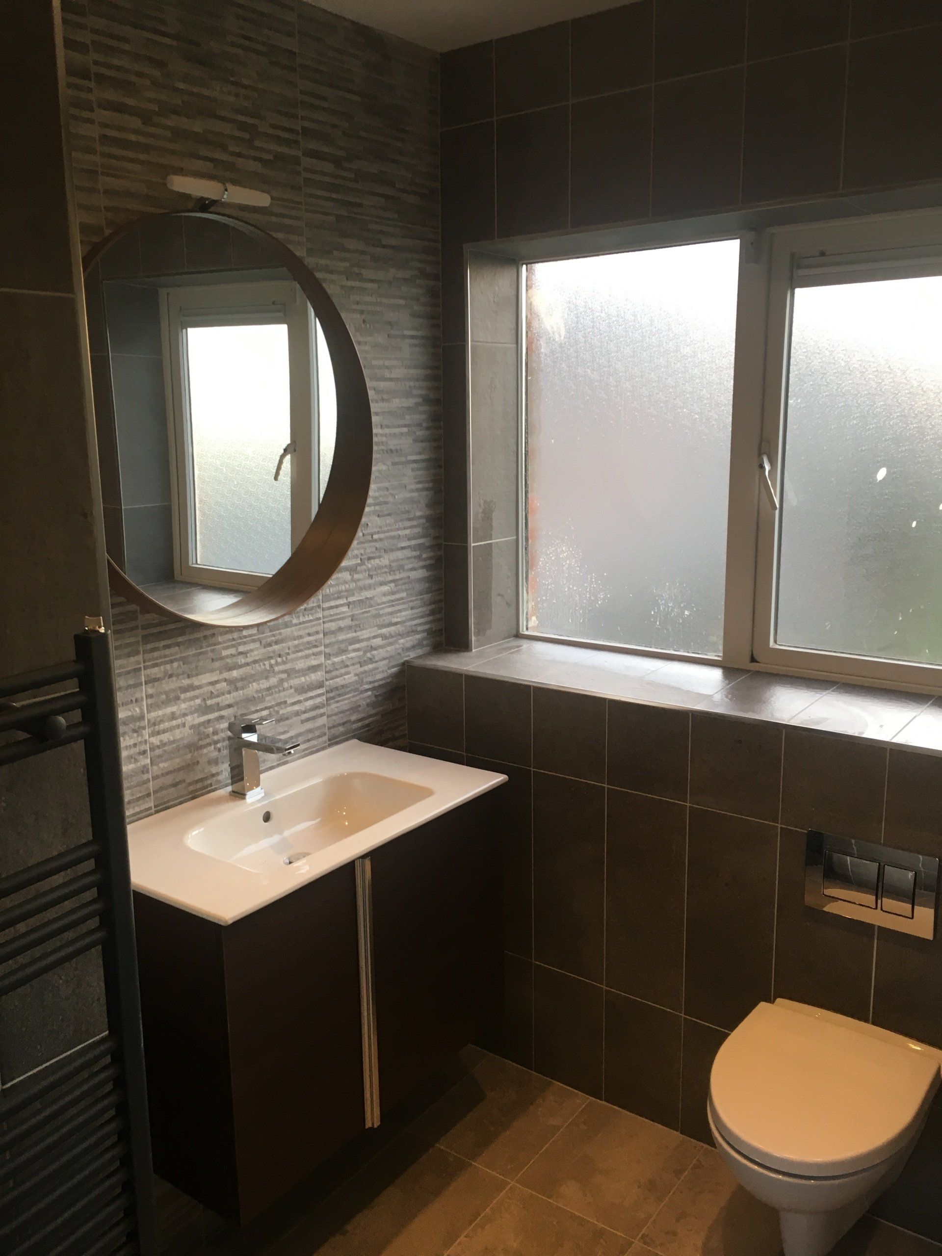 Bathroom dark and stone effect tiles dark wood wall hung Avila vanity unit and round mirror