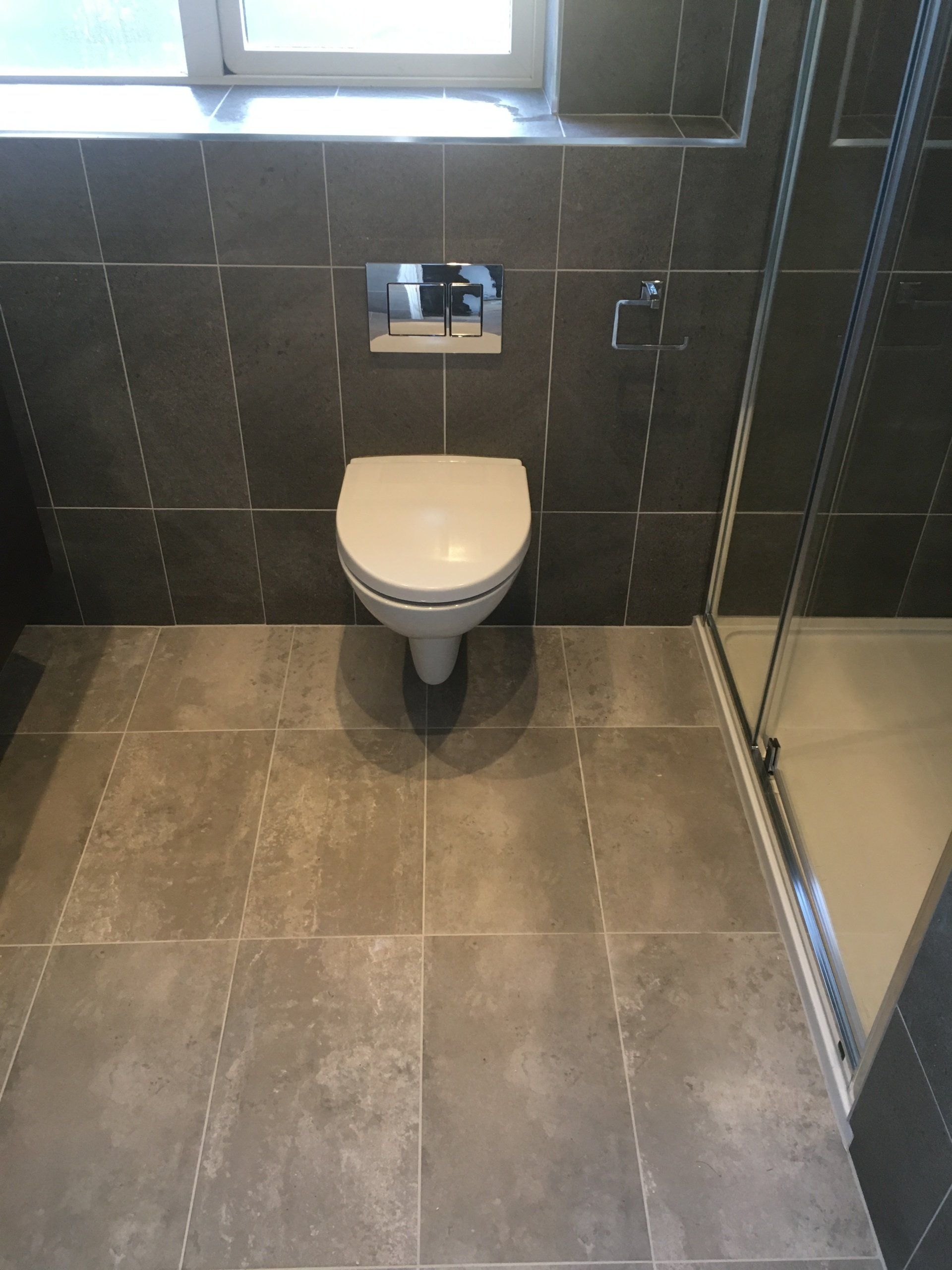 Bathroom dark tiles wall hung toilet and big shower enclosure