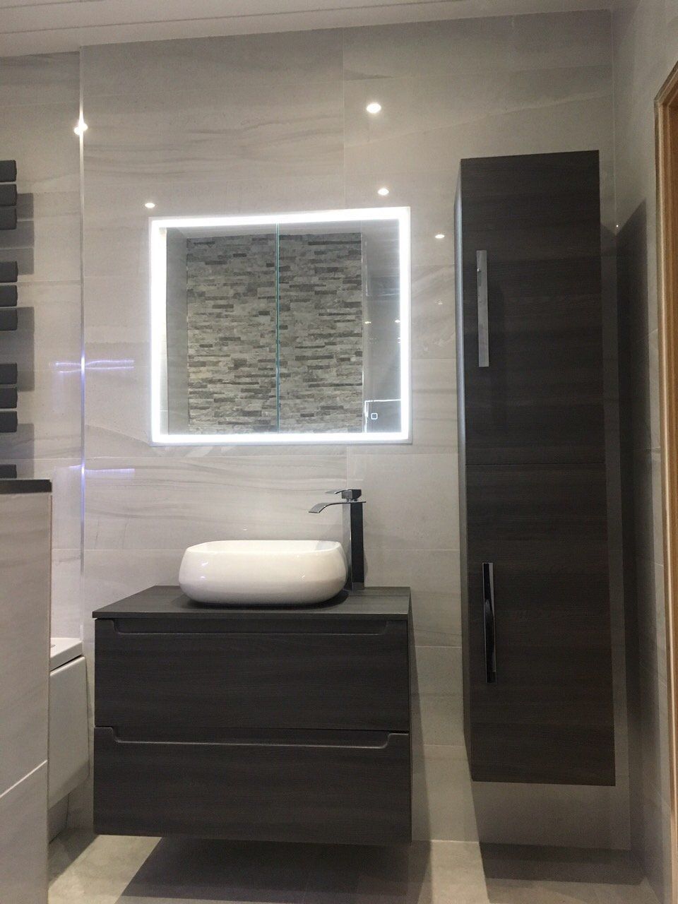 Luxury bathroom with grey tiles and dark wood wall hung vanity unt with countertop basin and a tallboy
