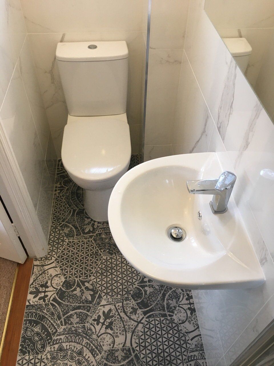 Small ensuite bathroom with marble effect wall tiles and patterned Morroccan alchimia floor tiles