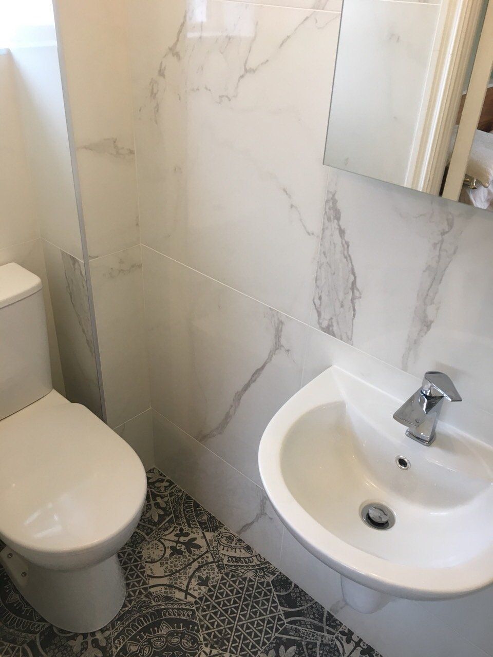 Small ensuite bathroom with marble effect wall tiles and patterned Morroccan alchimia floor tiles