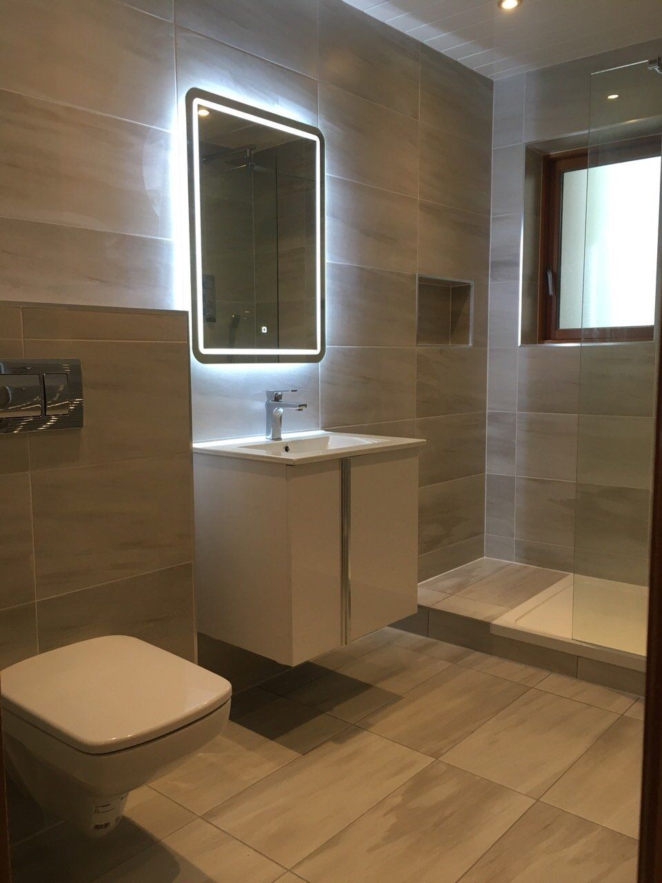 Bathroom grey tiles walk in shower wall hung vanity unit illuminated mirror and toilet