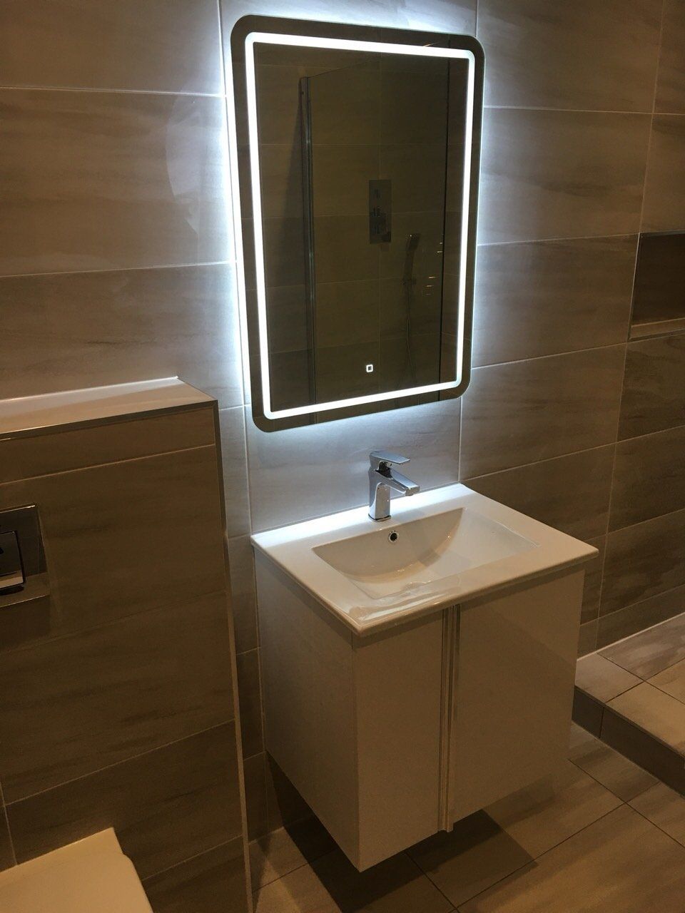 Bathroom grey tiles illuminated mirror and white wall hung vanity unit