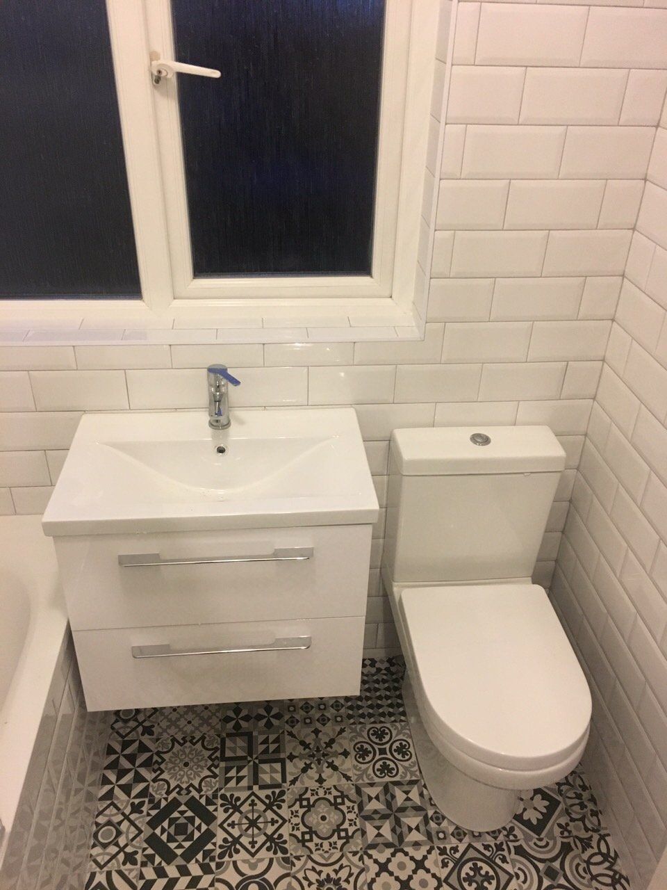 Bathroom with white subway wall tiles and black and white monochrome Morroccan patterned floor tiles and white vanity unit