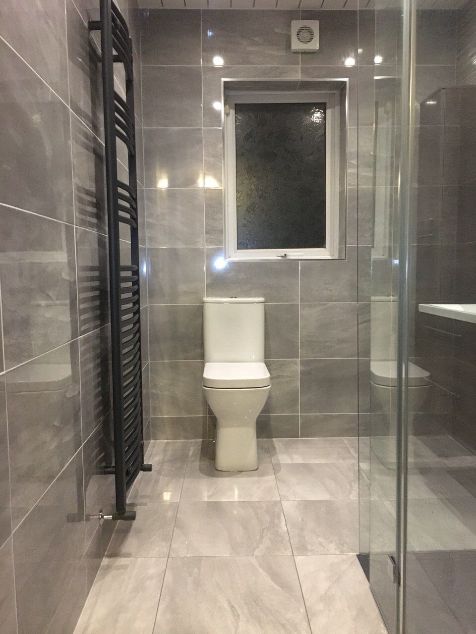 Anthracite heated towel rail, grey bathroom tiles, square toilet