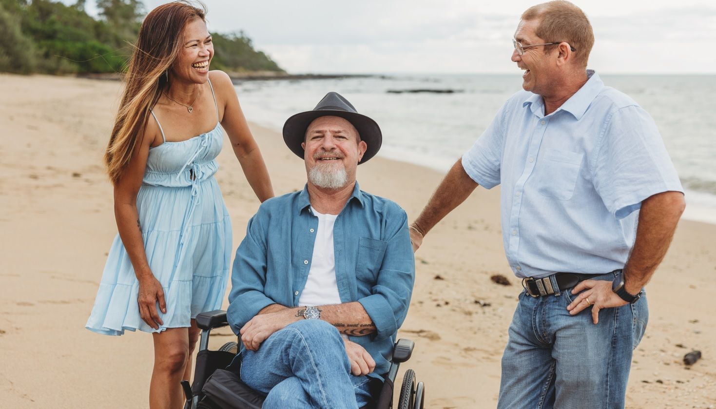 A Man is Helping a Man in a Wheelchair in a Living Room — Collis Care In Dundowran, QLD
