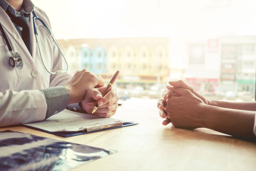 A Doctor is Sitting at a Table Talking to a Patient — Collis Care In Dundowran, QLD