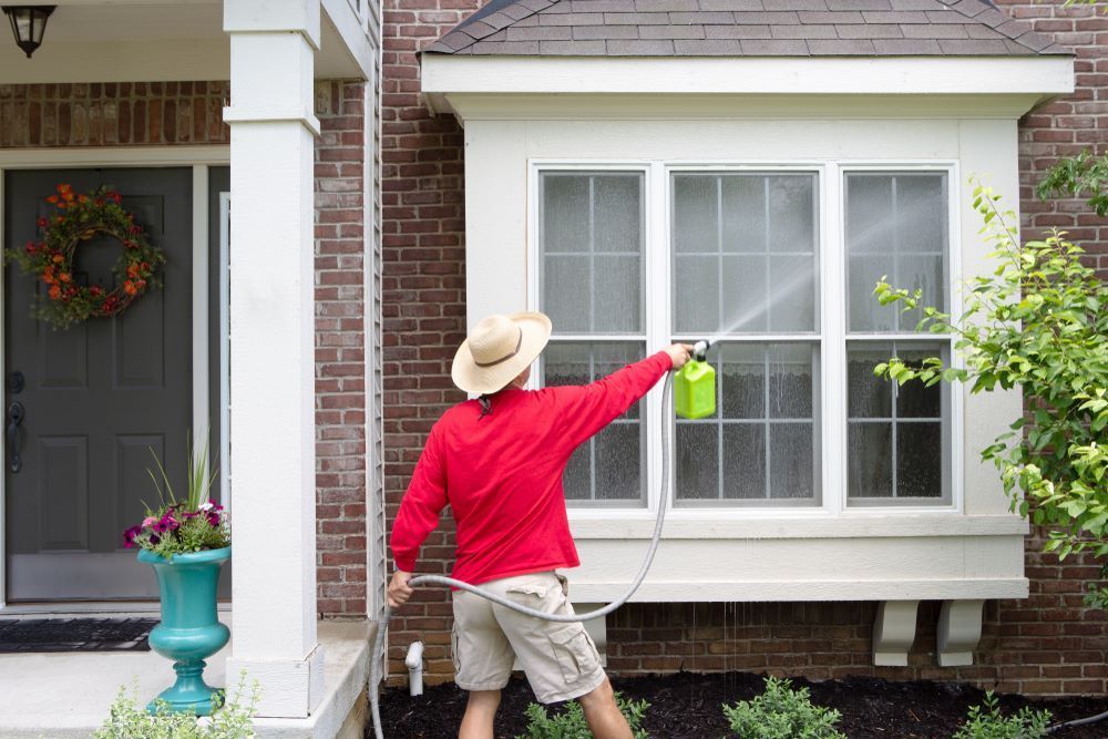 A Man is Spraying a Window With a Hose — Collis Care In Dundowran, QLD