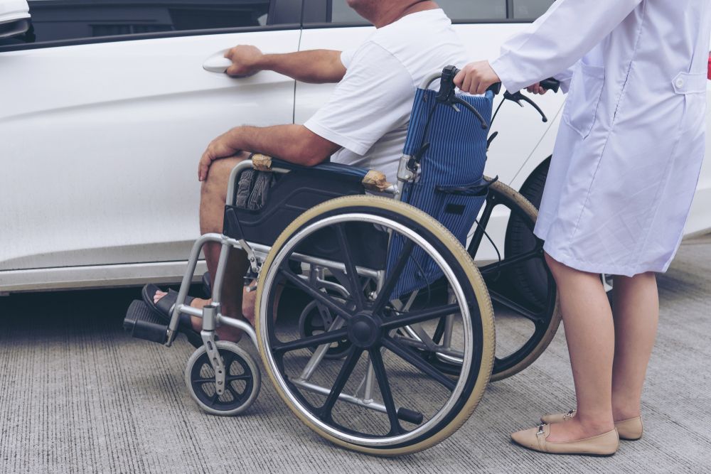 A Nurse is Helping a Man in a Wheelchair Into a Car — Collis Care In Dundowran, QLD