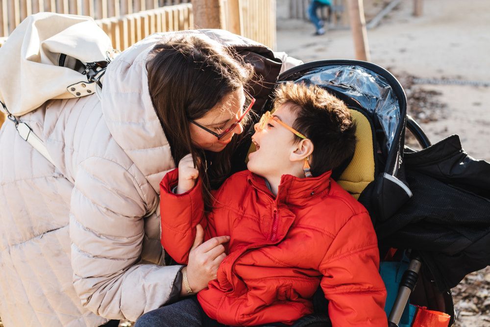 A woman is sitting next to a child in a stroller. — Collis Care In Dundowran, QLD