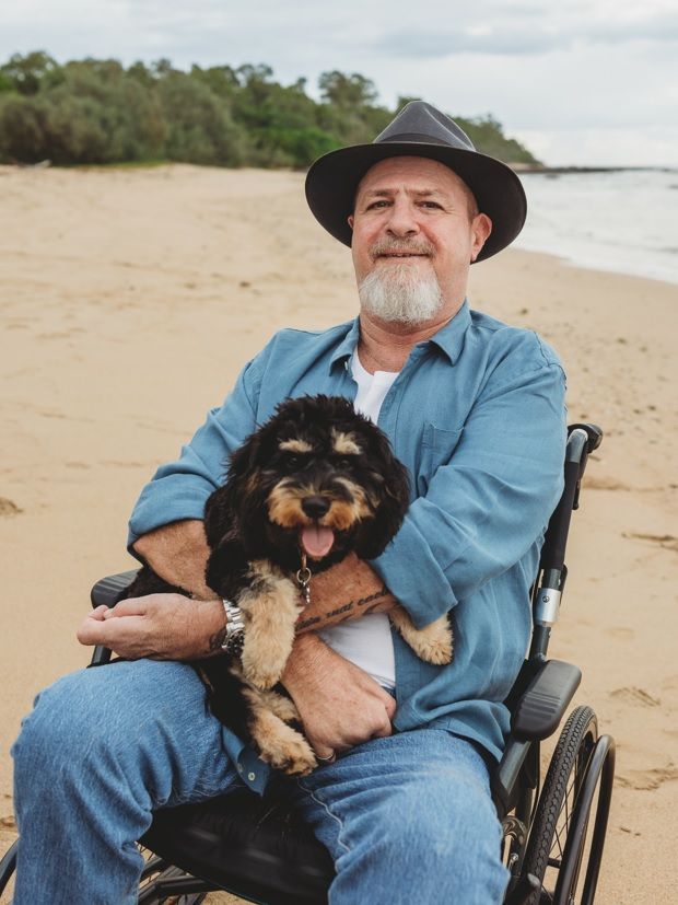 A man is sitting next to a boy in a wheelchair. — Collis Care In Dundowran, QLD